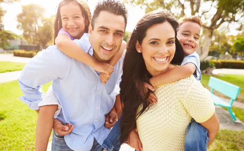 Family smiling at the park.